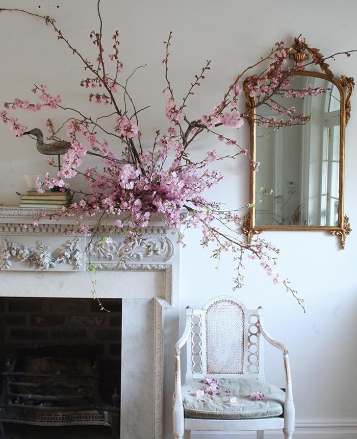 Creative mantel still life of pink blooming branches designed by Lucy Hunter