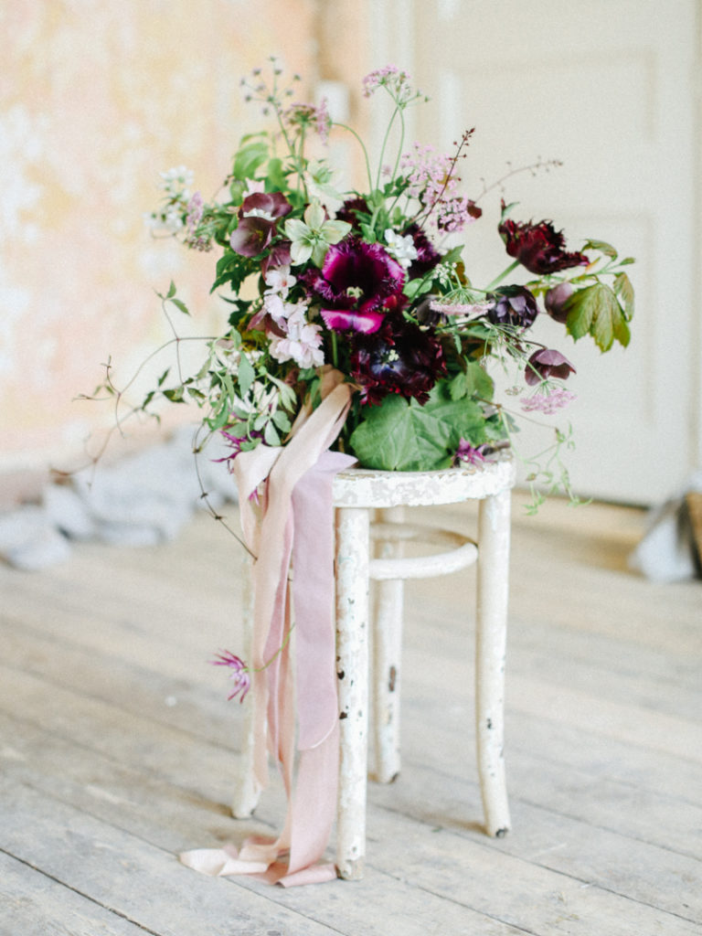A small floral arrangement on a white stool by Fiona Pickles