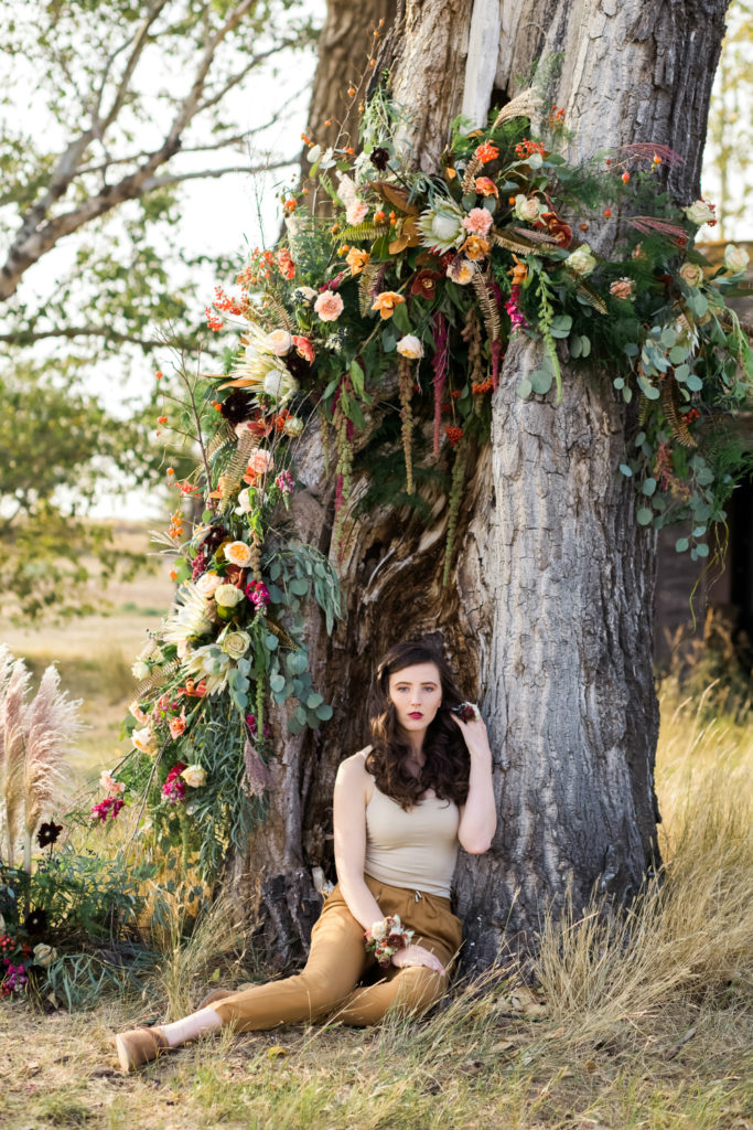 Flowers wrap around a tree above a model for a floral photoshoot by Chelsa Larson 