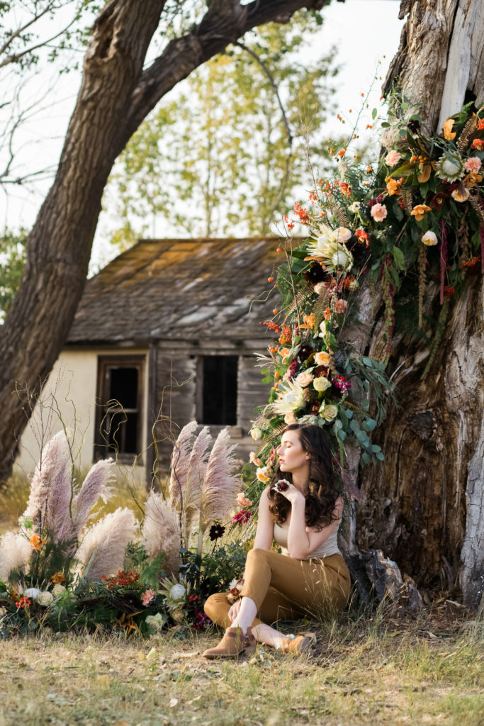 Flowers wrap around a tree above a model for a floral photoshoot by Chelsa Larson 