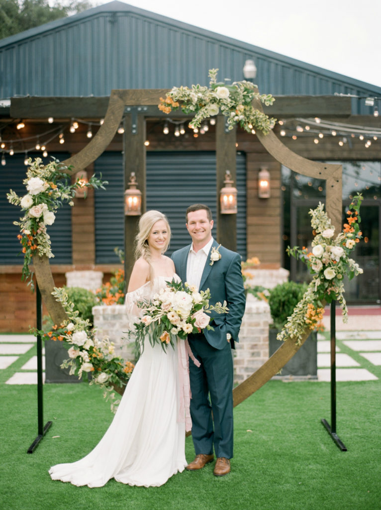 A bride and groom pose with floral design by Maggie Bailey, for Building a Wedding Business