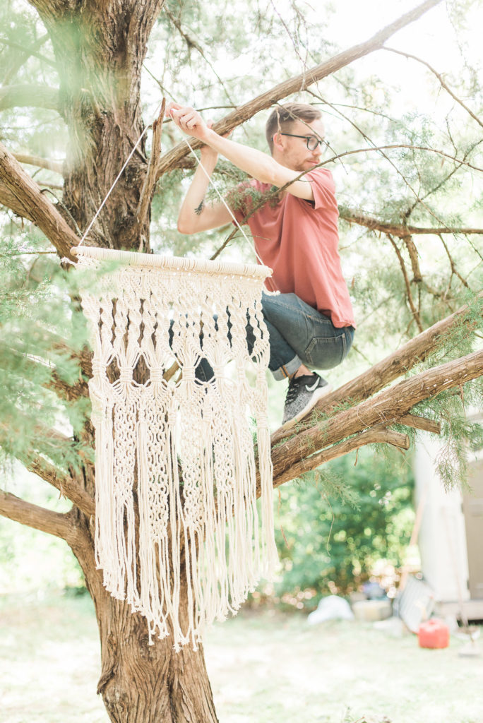 Gabe Miller hangs a tapestry from a tree in the BB Garden