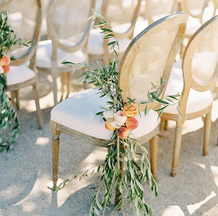 A floral design with peaches on a wooden chair at a wedding by Morgan Anderson