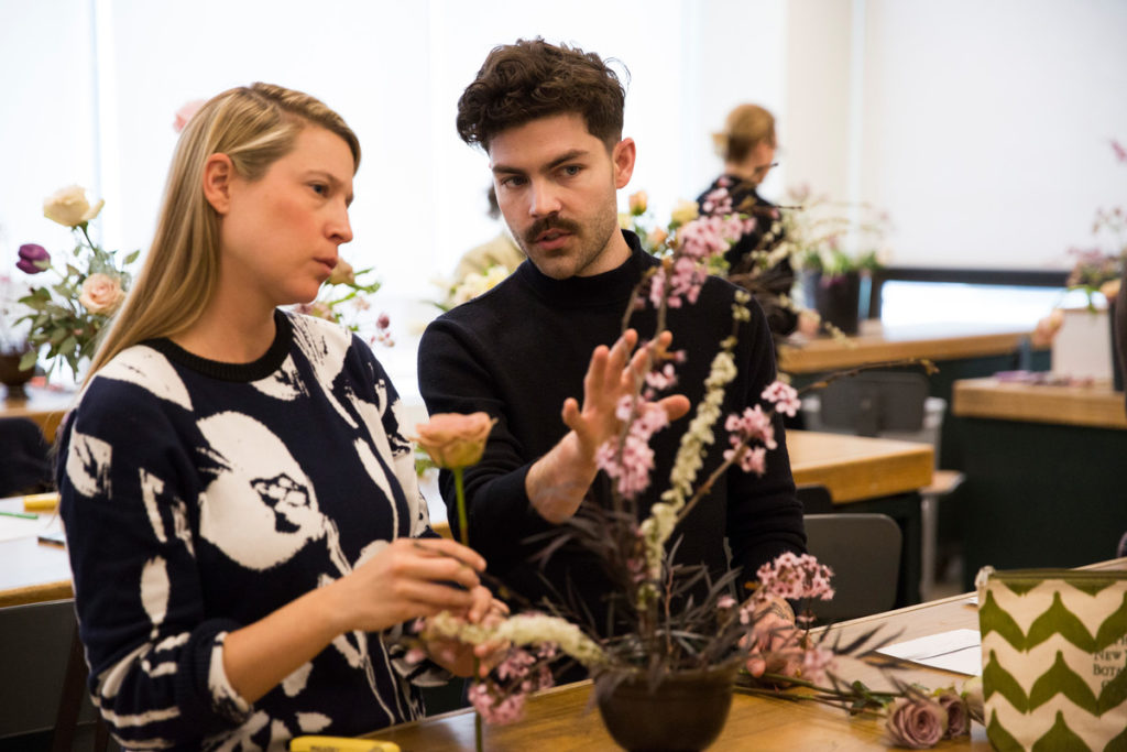 Two attendees work on a floral arrangement at a NYBG summer intensive
