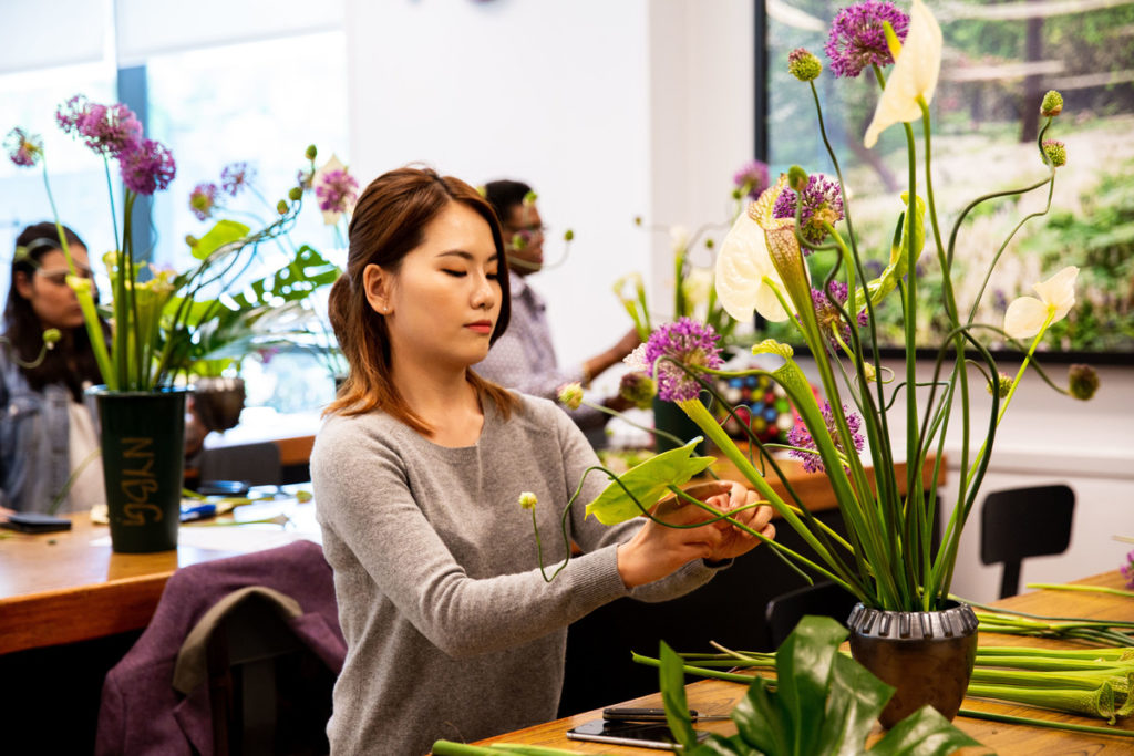 A floral designer works on a tall arrangement at a NYBG summer intensive