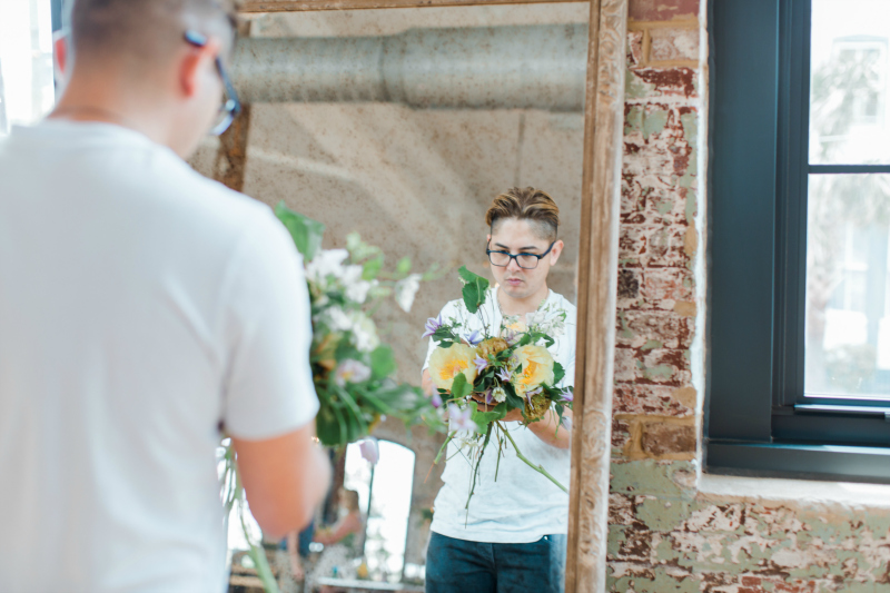 An attendee looks at a bouquet in the mirror at the Mayesh Design Star Workshop 