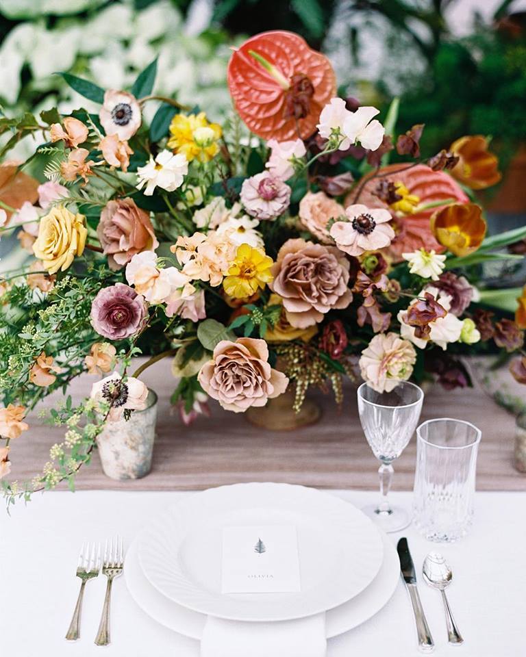 A floral centerpiece with yellow roses and coral anthurium by Eatherley Schultz