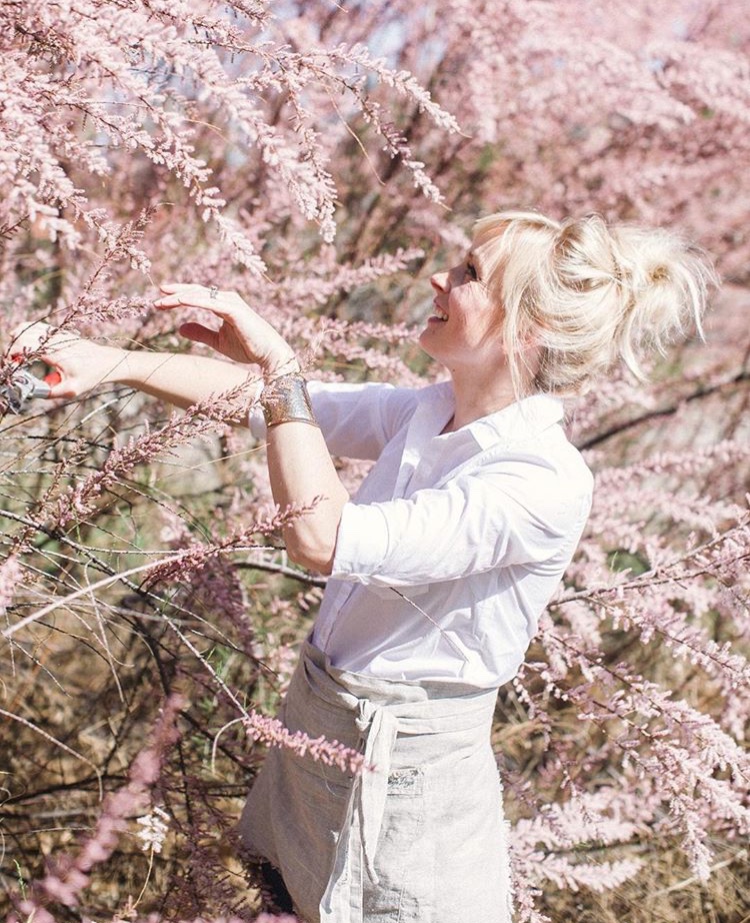 Kelly Mendenhall cuts a branch off of a pink floral tree