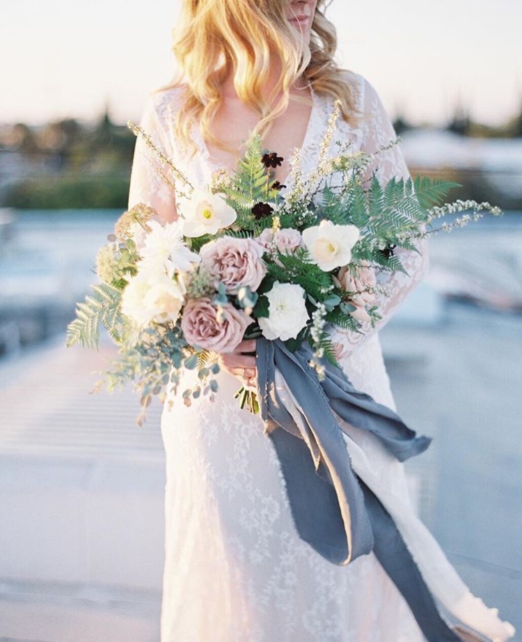 A bride holding a bouquet with gray fabric by Janelle Wylie