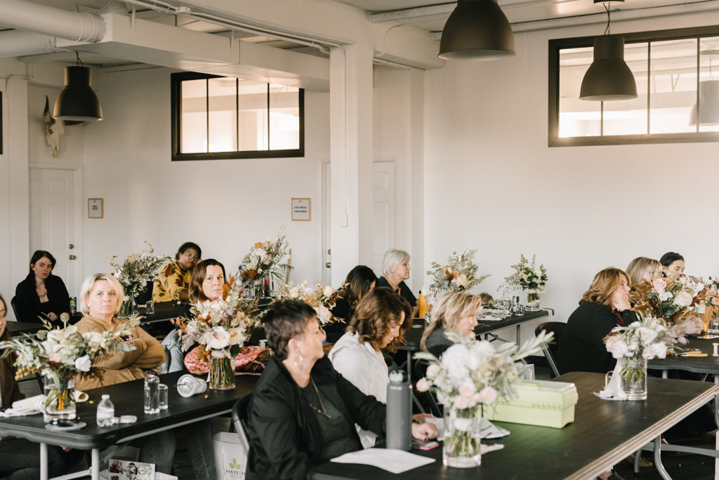 Attendees are in session at the Mayesh Design Star Workshop sitting in rows with floral arrangements in progress