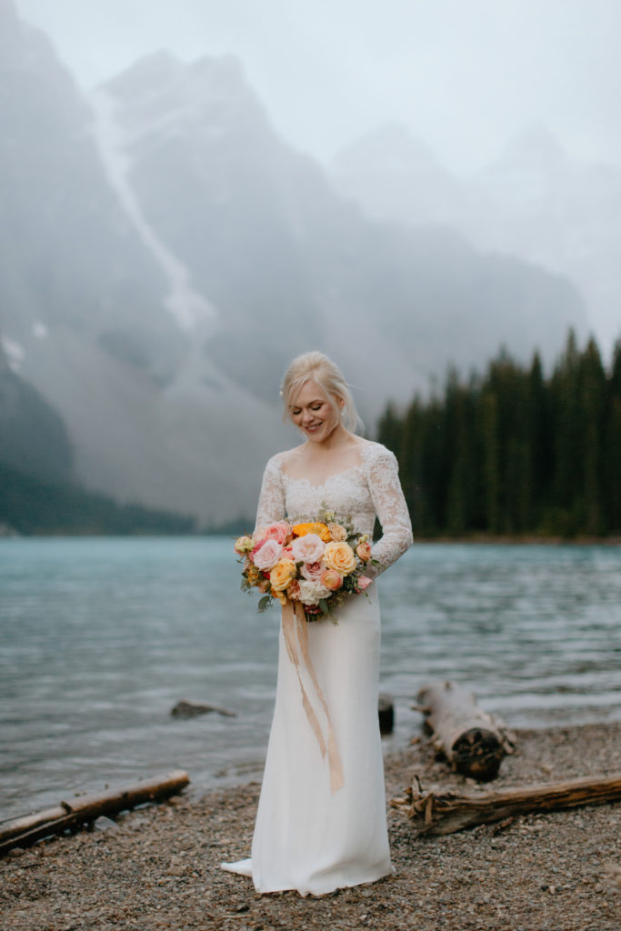 A bride holding a bouquet of flowers in the Rockies at Moraine Lake