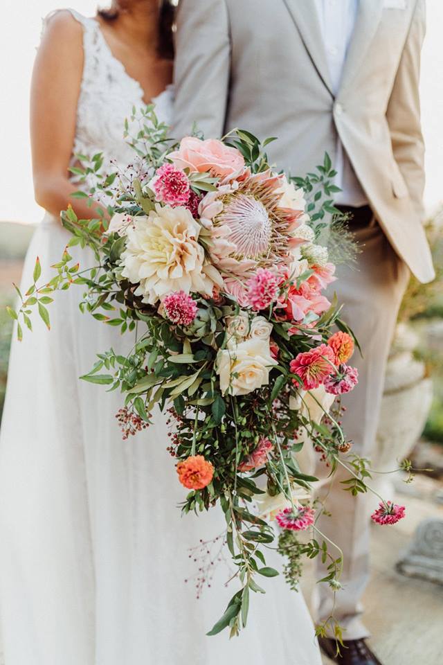 A bride and groom with a large, pink bridal bouquet by Coral Shortt