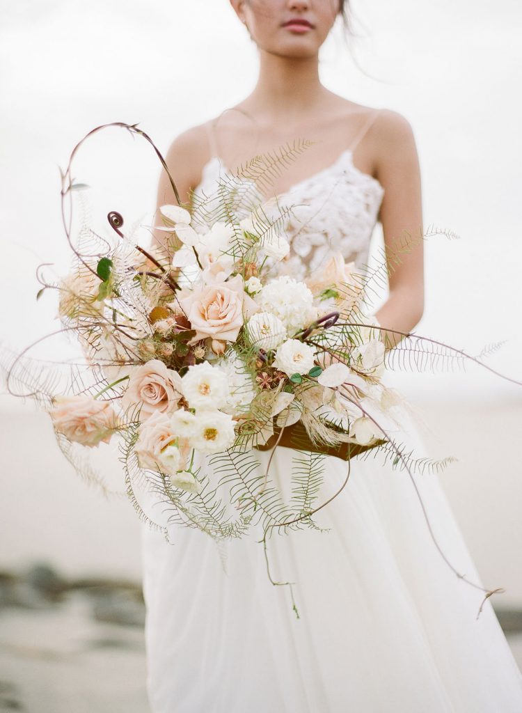 A model for a bridal photo shoot holding a large white bouquet