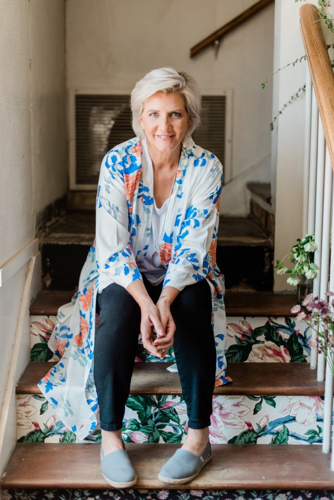 Parie Donaldson sits on a floral-painted staircase