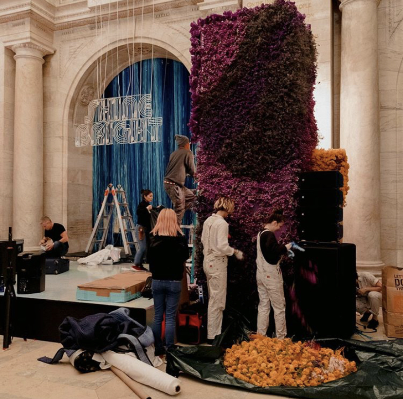 Liza Lubell helps set up a large purple floral installation