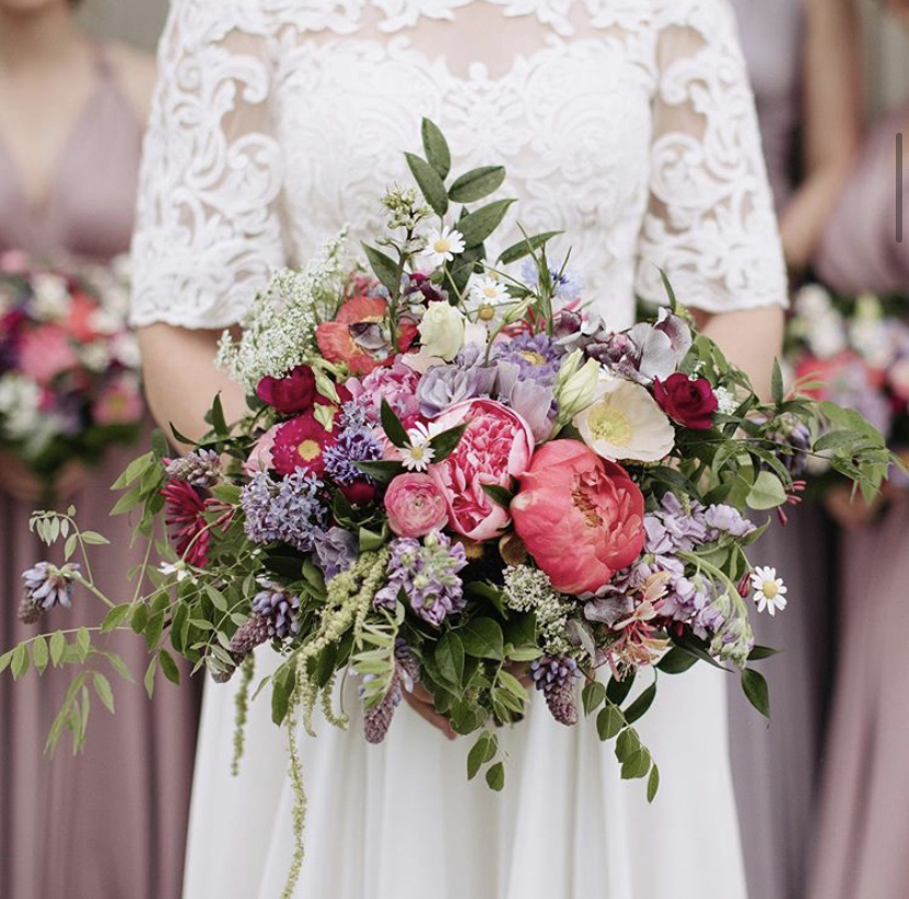 Bridal Bouquet of peonies, poppies and lavender flowers grown by Harmony Harvest Farm held by bride in white lace wedding gown