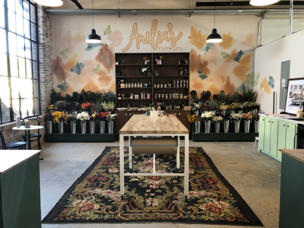 The flower bar at Amelia's Flower Shop with wood work table in center on vintage rug