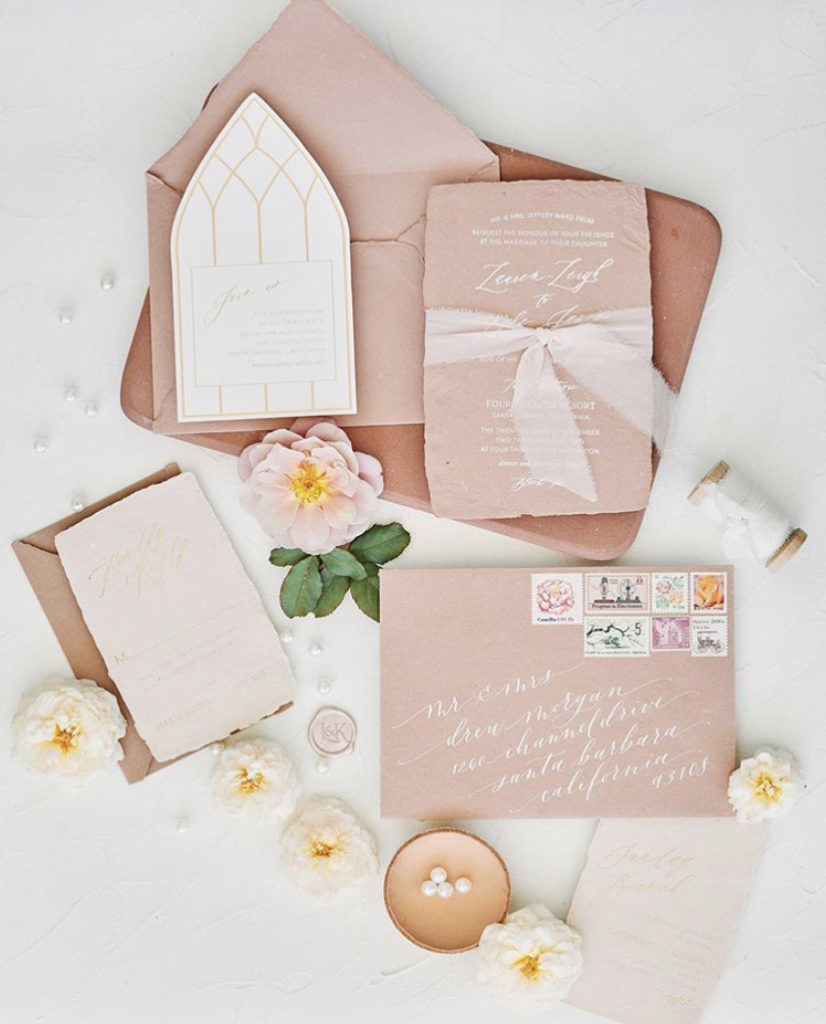 flowers and ribbon complete a pink wedding invitation suite flatlay