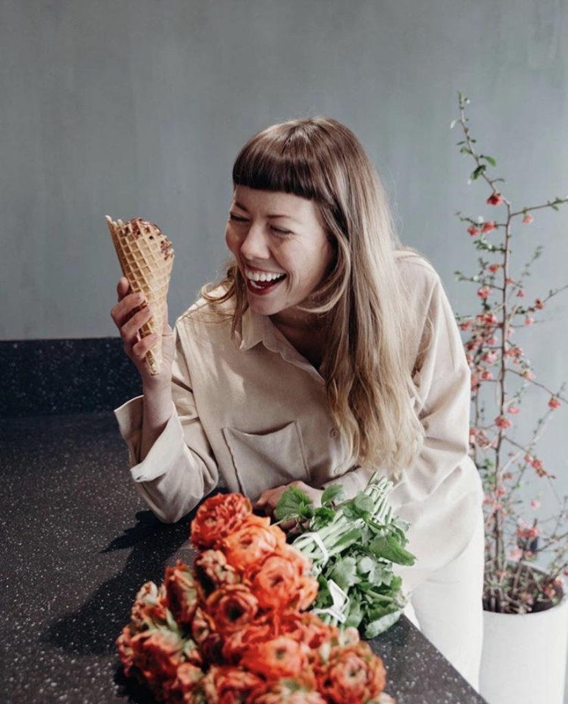 Floral designer Alyssa Lytle eats an ice cream come while working with flowers in her studio