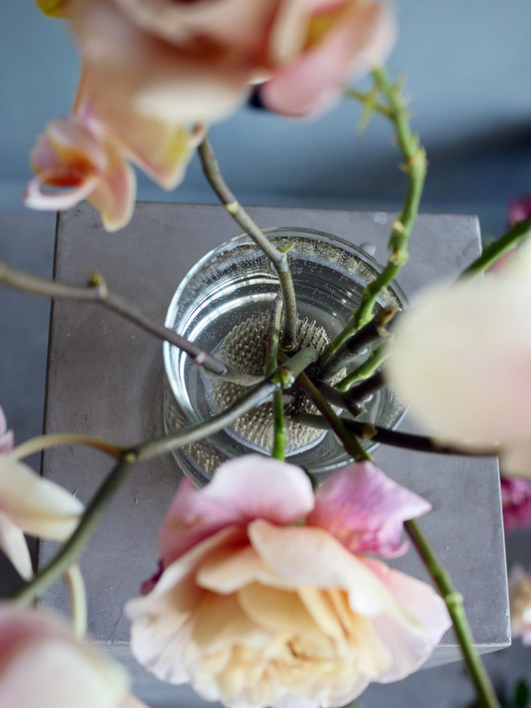 Close up of flower stems in a vase arrangement and pin frog