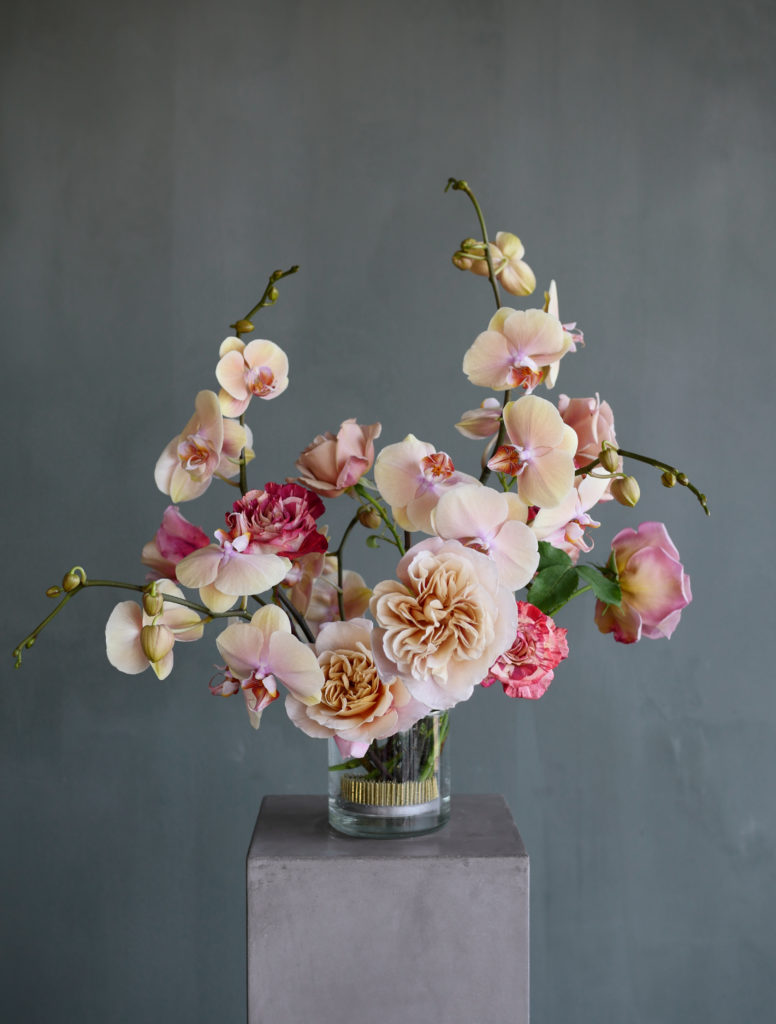 Peach and pink flower arrangement with orchids and roses in pin frog
