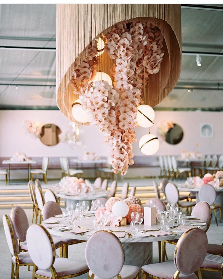 Orchid and fringe chandelier designed by Rebecca Grace at Natural Art flowers hangs over a reception table