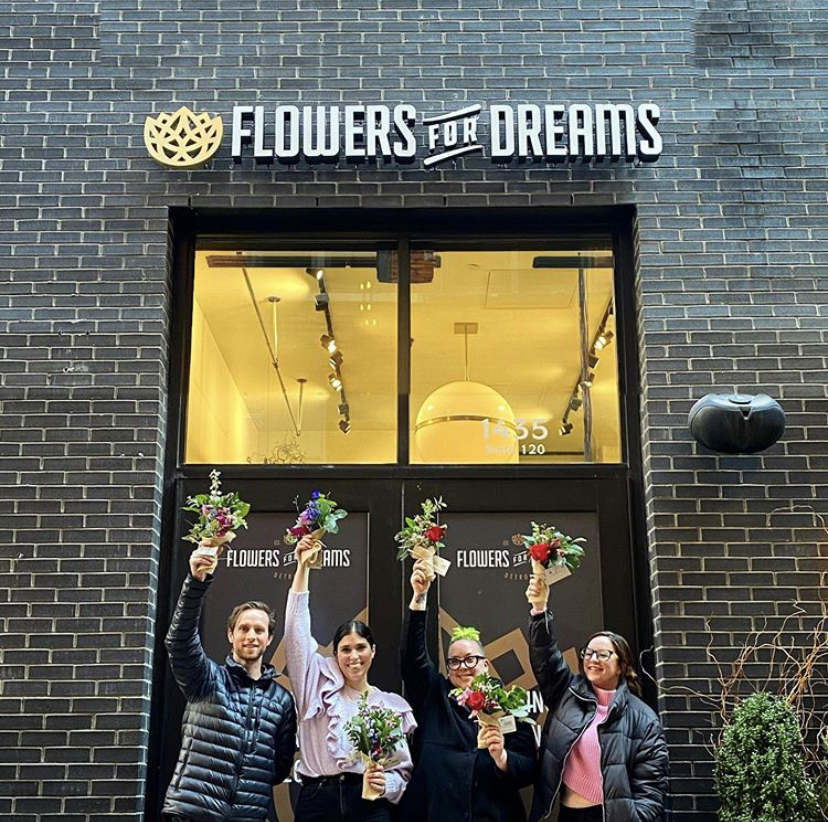 Customers standing outside the newest location of Flowers for Dreams holding up bouquets