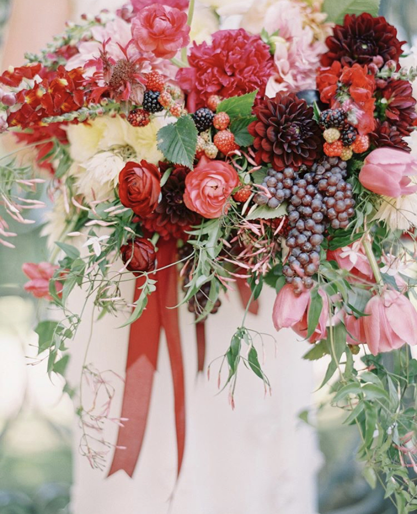 Sweet Root Village bridal bouquet of reds and purples including dahlias, grapes, tulips, ranunculus, berries, and jasmine