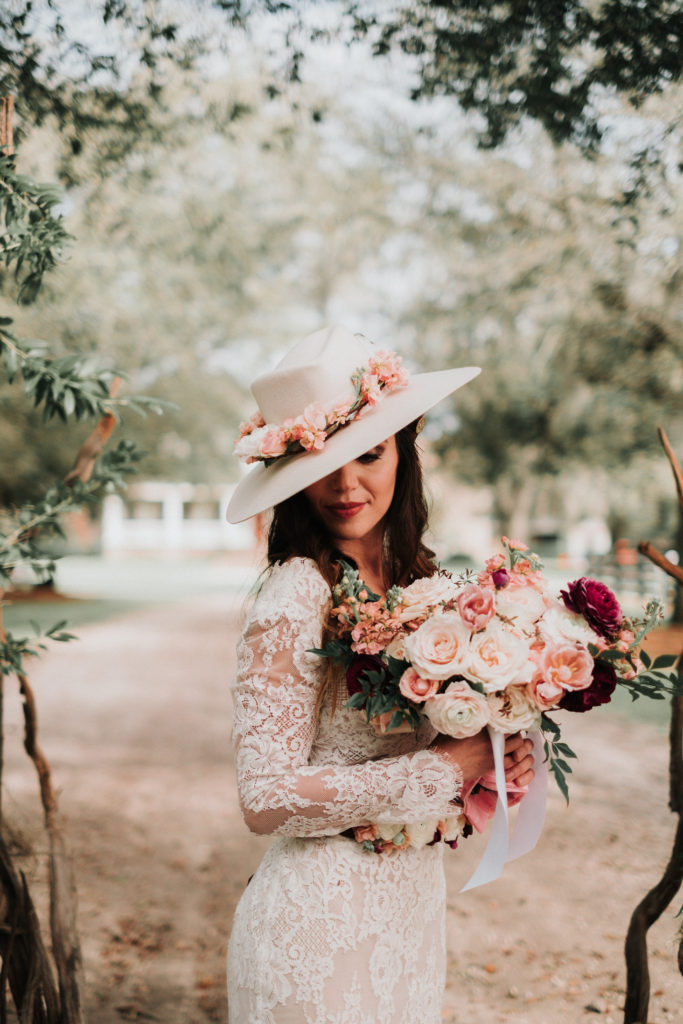 Bride wearing a flower adorned hat and holding a bridal bouquet for a styled shoot