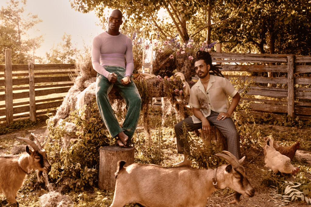 two men in a goat pen for a high fashion photo shoot