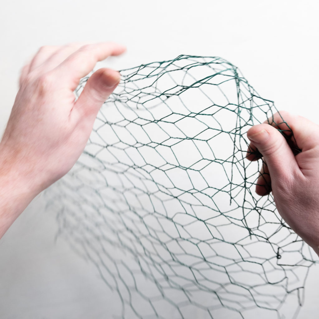 rolling a piece of chicken wire to use as an armature in a foam free sustainable floral design