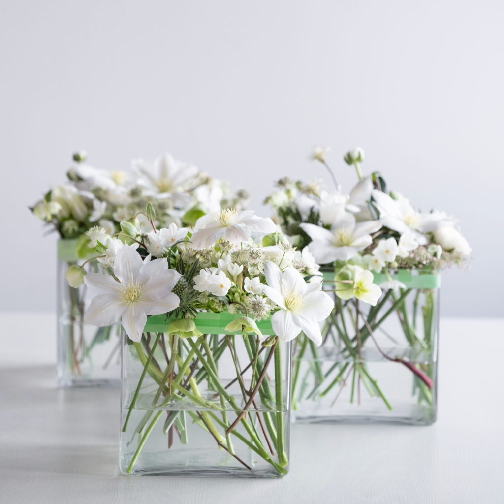 floral tutorial showing three glass vases with white flowers and green washi tape grids for easy placement of stems