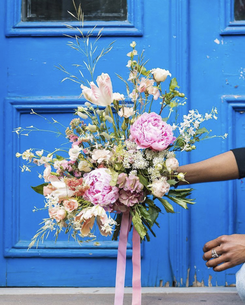 Brooklyn Blooms bridal bouquet of pink peonies and tulips in front of a blue door