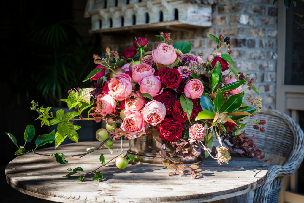 Floral arrangement on outside patio table packed with pink and red garden roses from Alexandra Farms
