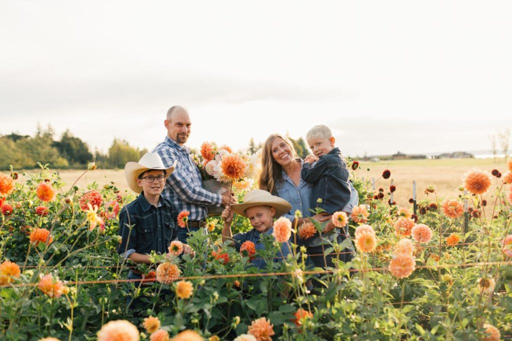 Deanna Kitchen, founder of Growing Kindness Project , standing in a field of orange dahlias with her family