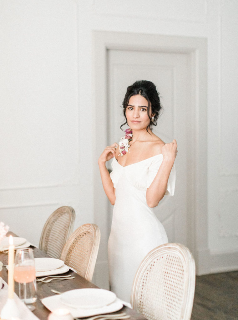Bride in white dress and wearable florals on clavicle