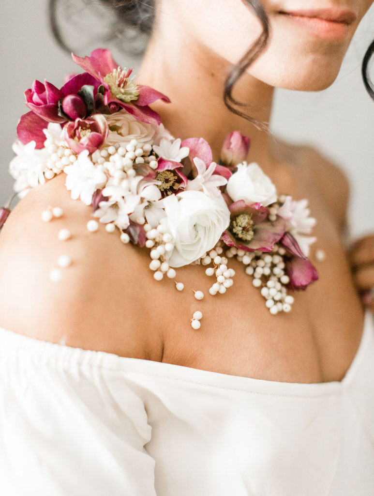 Wearable florals worn as a corsage applied directly to skin of bride in shades of white and mauve