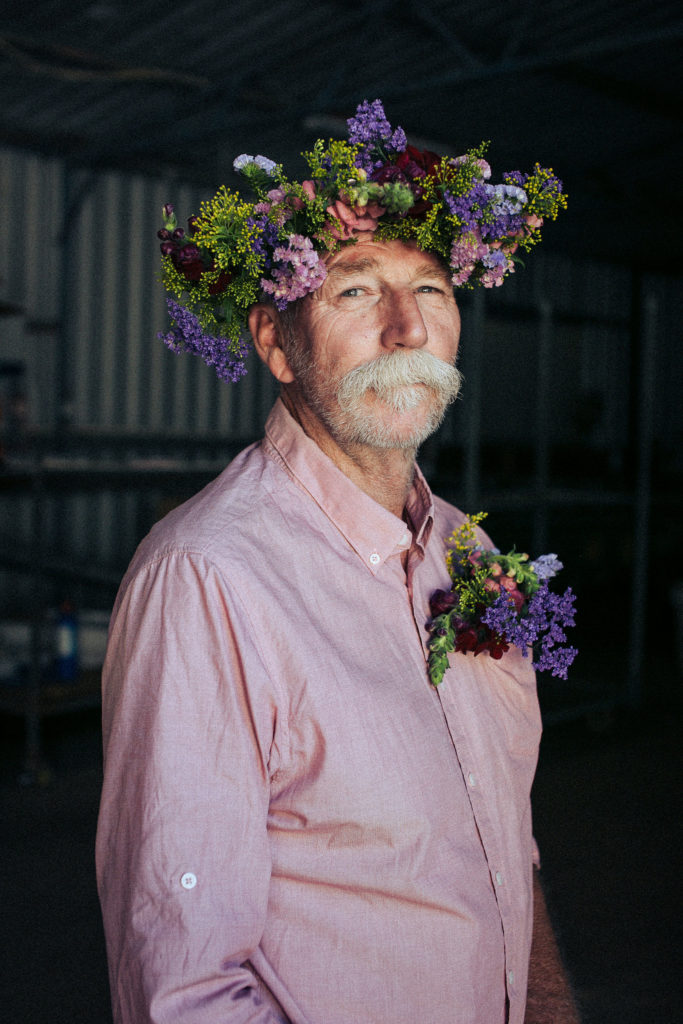 Flowered fella wearing a flower crown of pink and purple flowers with matching pocket square