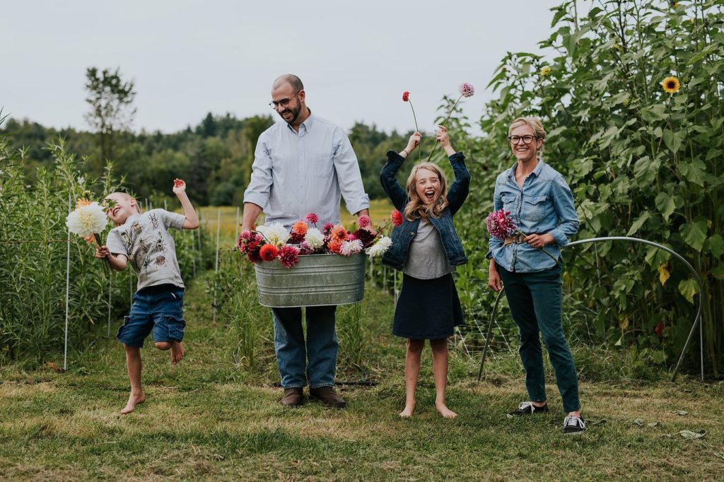 Family who owns Little Farmhouse Flowers standing in the flower field with buckets of flowers