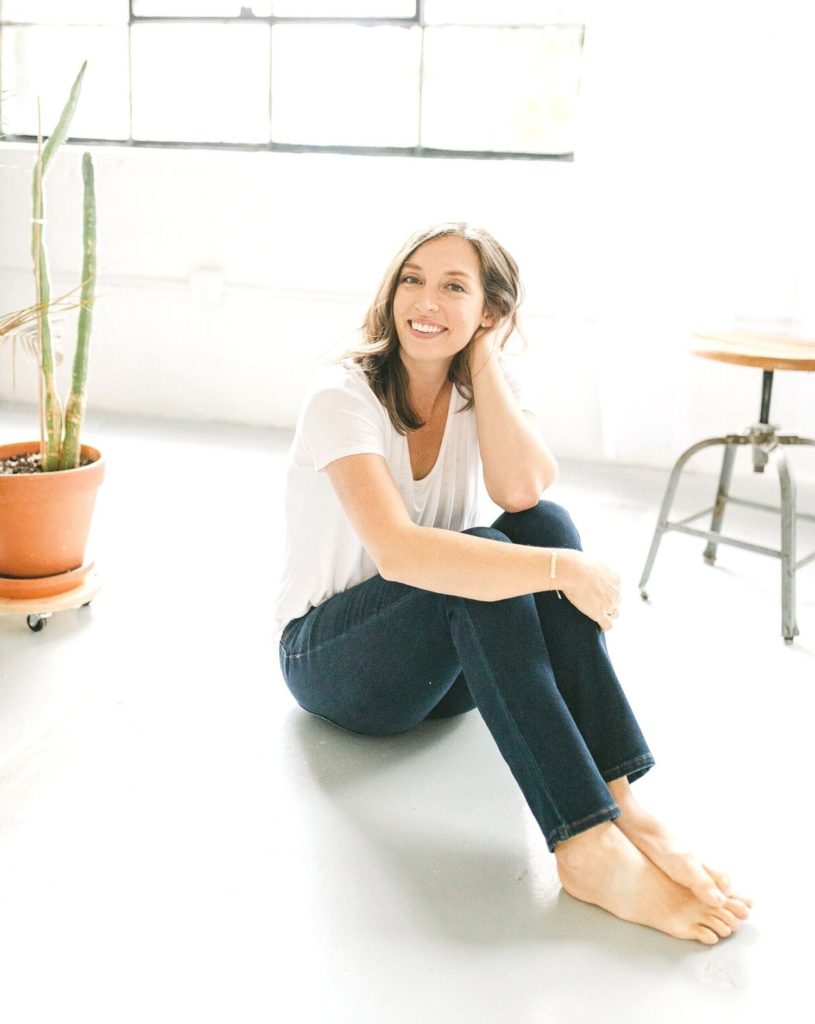 Career and life coach for creative entrepreneurs Julie Tobi sitting on the floor of her studio