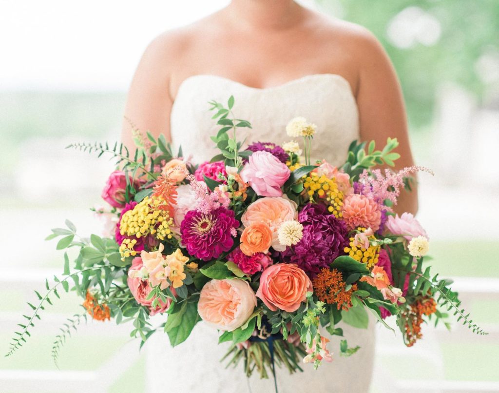 Bride holding a bouquet of yellow, peach, and hot pink American grown flowers designed by Petals by the Shore and The Floral Source
