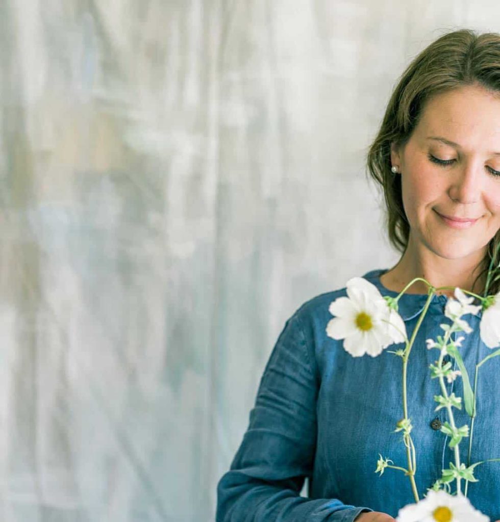 Floral designer Sarah Diligent holding a stem of white cosmos