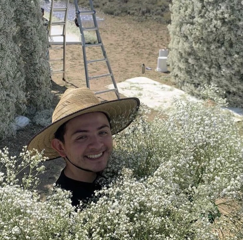Floral freelancer Jesse Camargo surrounded by baby's breath during a floral installation at an outdoor Wyoming wedding