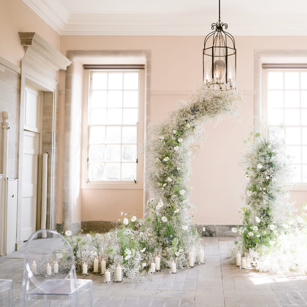 White cosmos and baby's breath deconstructed arch floral installations designed by Joseph Massie for an intimate wedding in a neutral space with a brick floor