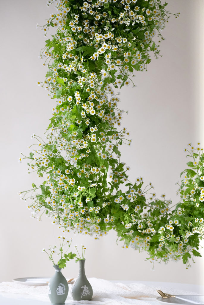 Floral installations hanging above a table in colors of green, white, and yellow