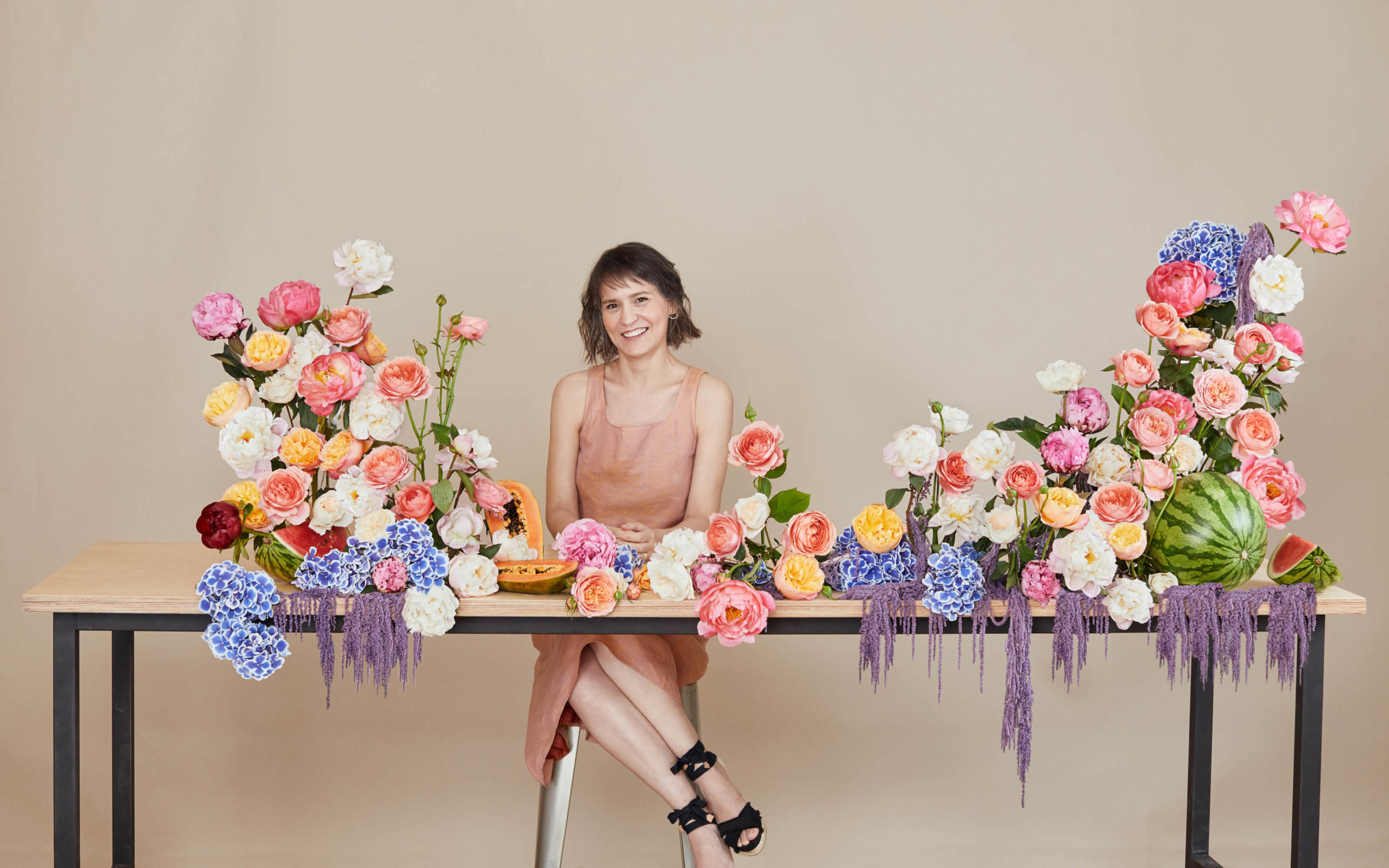 Madrid Flower School founder Sylvia Bustamante Gubbins sitting behind a table of flowers