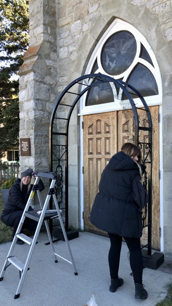 Flowers by Janie team installing an iron arch in front of a chapel