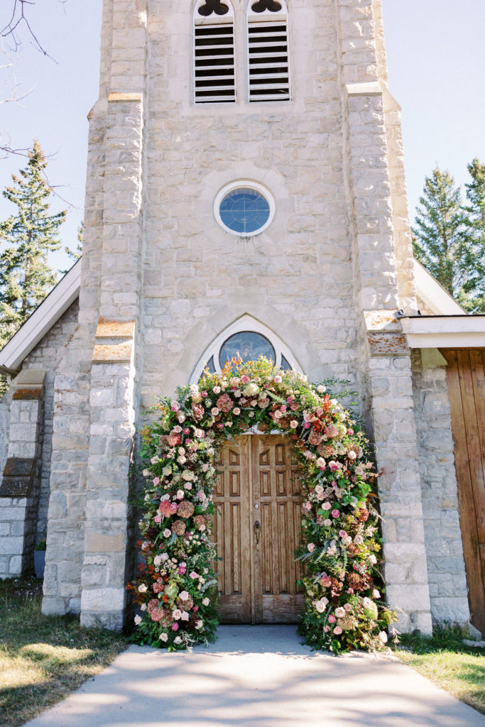 Floral arch in front of a stone chapel