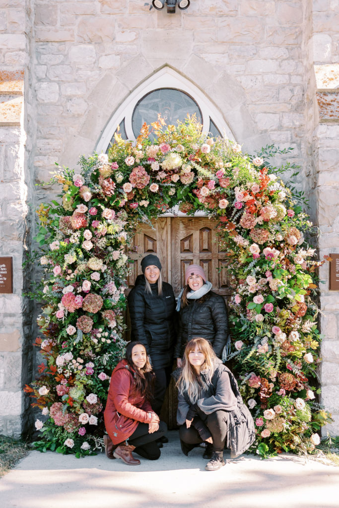Flowers by Janie team standing under the foam free floral arch they created
