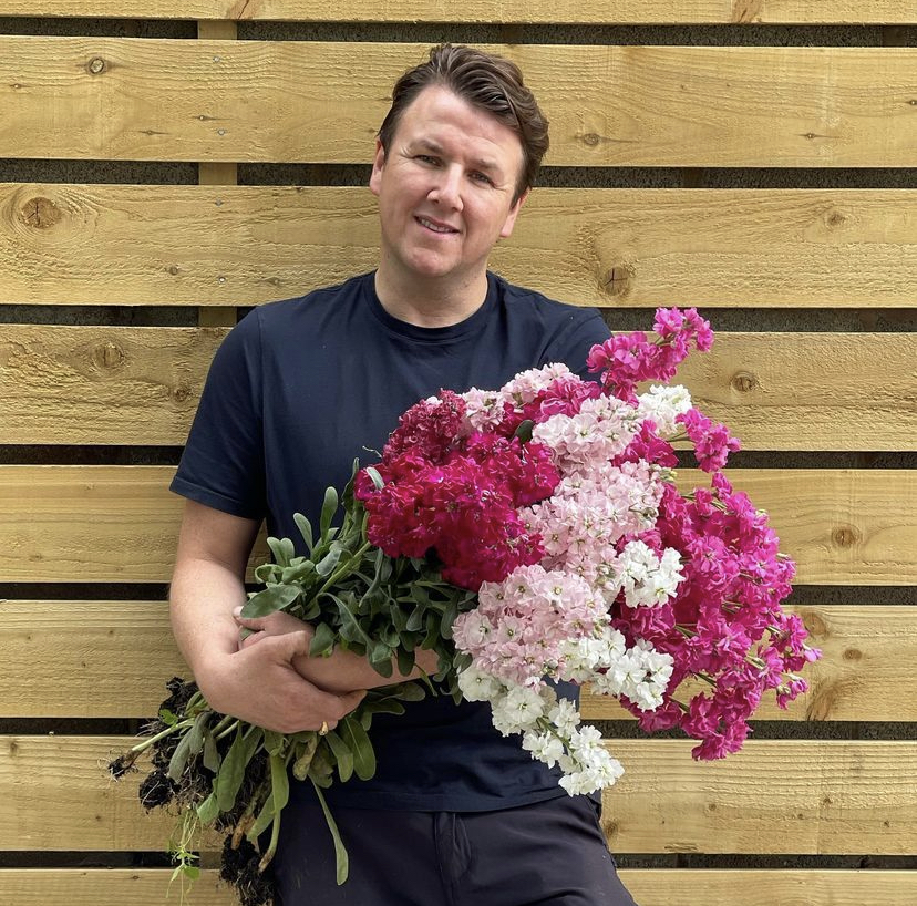John Gibbons, owner of Lakes and Rivers Flower Farm, holding a bundle of pink flowers